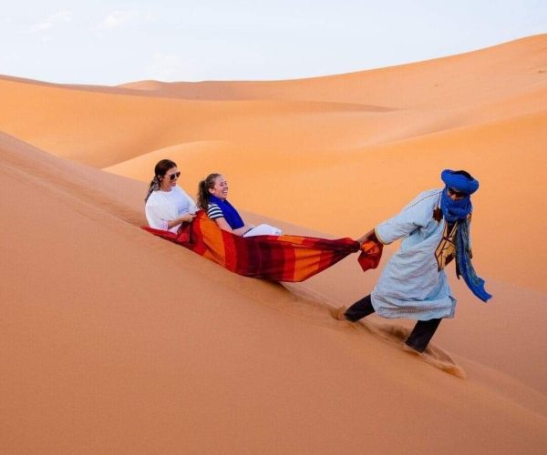 berber man playing with two women in sahara desert