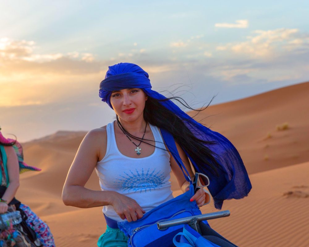two women riding camel in sahara