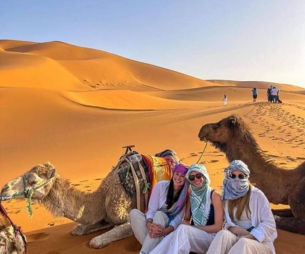 women-tourists-sitting-near-camels-in-desert